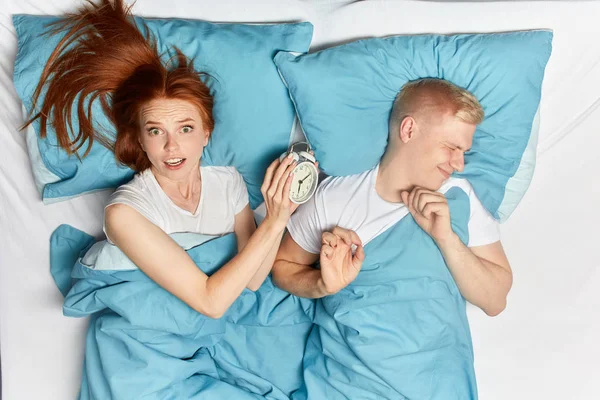 Нервничающая шокированная девушка и ее спящий муж опаздывают на встречу — стоковое фото