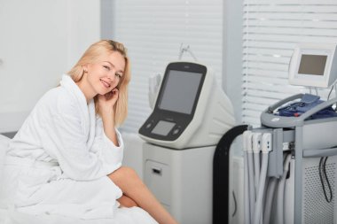 kozmetoloji için araçların yanında oturan beyaz rahat bornoz pozitif model