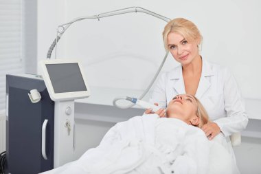 müşterilerine çene kozmetoloji aracı tutan çekici yetenekli kozmetolojist
