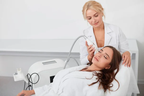 Utalentowanych kobiet podnoszenia lekarz, oczyszczanie skóry twarzy pacjenta — Zdjęcie stockowe