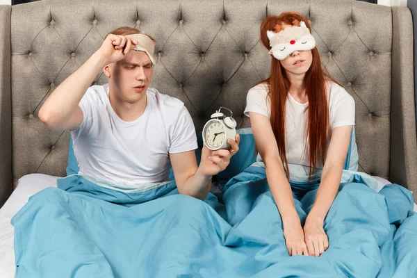 Hombre frustrado infeliz mirando a través de la máscara ocular en el despertador — Foto de Stock