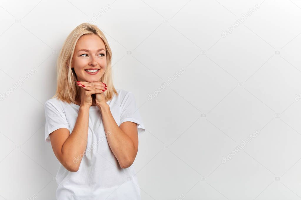 delighted charming girl with palms under chin looking with flirt aside