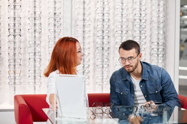 optik mağazasında adama gözlük gösteren iyi görünümlü gözlükçü