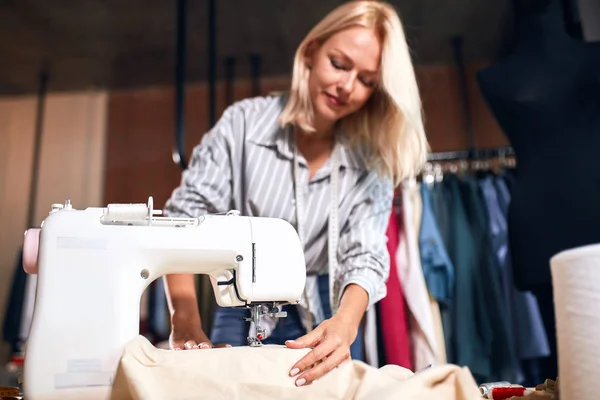Sorrindo adorável alfaiate teste nova máquina de costura moderna — Fotografia de Stock
