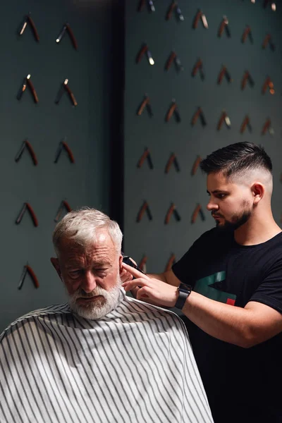 talented stylist making new hairstyle for old man