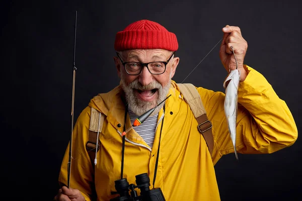 Happy old bearded fisherman is happy as he has cought fist fish