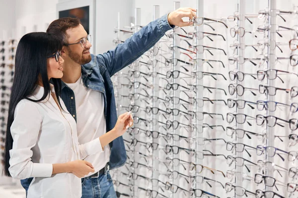 Barbudo handsoem sonriente hombre tomando gafas de la estantería para probarlos en —  Fotos de Stock