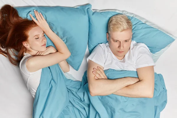 Blonde man met slapeloosheid liggend in bed met open ogen. zijn vrouw is in slaap gevallen — Stockfoto