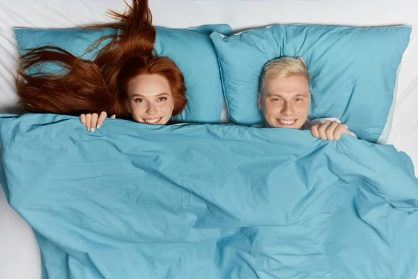 Homme blond positif et gingembre femme couché sur le lit — Photo