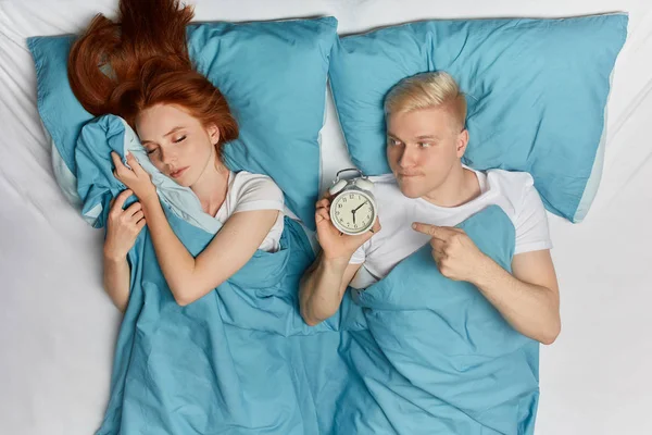Serieuze blonde man met wekker wakker jonge Giger vrouw — Stockfoto