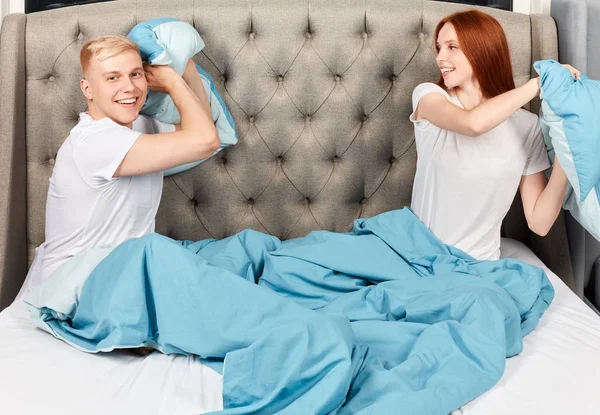 Jeune couple drôle se battant avec des oreillers sur le lit — Photo