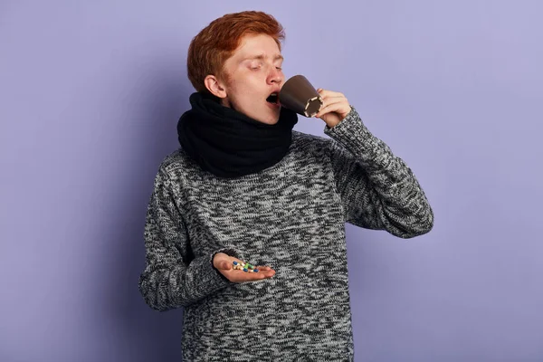Молодой человек пьет воду и ест болеутоляющее — стоковое фото