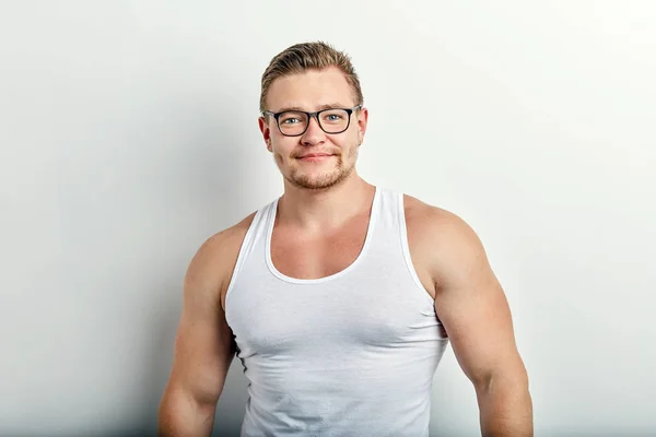 Jovem forte bonito alegre homem em branco singlet no fundo branco . — Fotografia de Stock