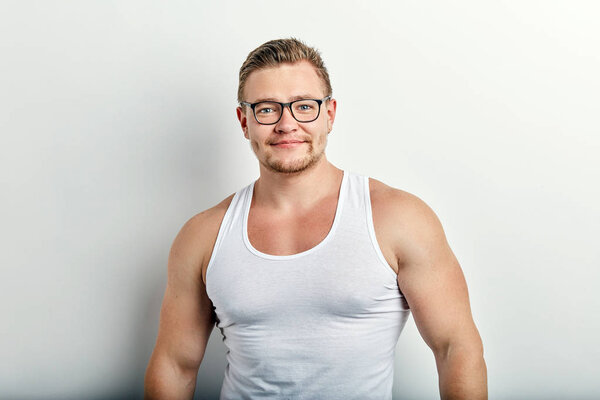 young strong handsome cheerful man in white singlet on white background.
