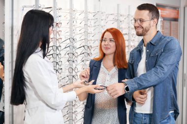 genç neşeli erkek ve kadın optik mağazasında gözlük satın alma
