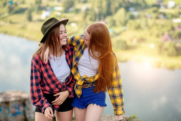 Twee vrolijke mooie meiden op de top van de berg lachen om iets — Stockfoto