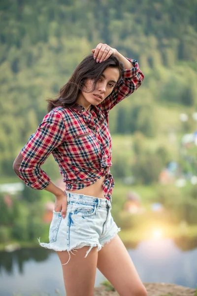 Atractiva chica apasionada en camisa a cuadros y pantalones cortos mirando a la cámara — Foto de Stock