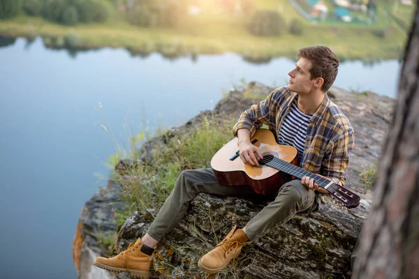 talented creative man playing a guitar on the mountain