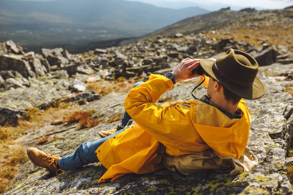 Joven excursionista descansando en las montañas mirando a través de binocular a la distancia — Foto de Stock