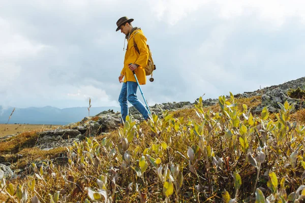 Homem bonito com uma mochila caminha sozinho em uma montanha — Fotografia de Stock