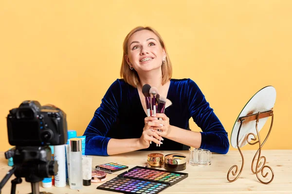 Fröhliche Beauty-Bloggerin Mädchen hält ein paar Make-up-Pinsel in der Hand und blickt nach oben — Stockfoto