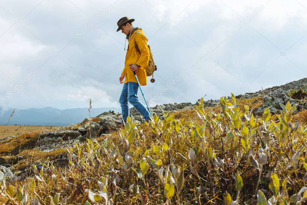 handsome man with a backpack walks alone on a mountain