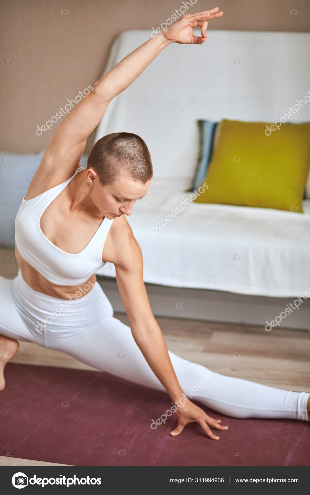 Beautiful caucasian woman exercising yoga stretching legs warm up in light room at home Stock Photo ufabizphoto 311994936