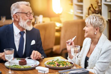 Üst düzey modern çift restoranda Iqos ve elektronik sigara kullanarak yemek yiyor.
