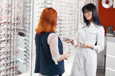 Genç yetenekli gözlükçü gözlük almak için müşteriye danışıyor.