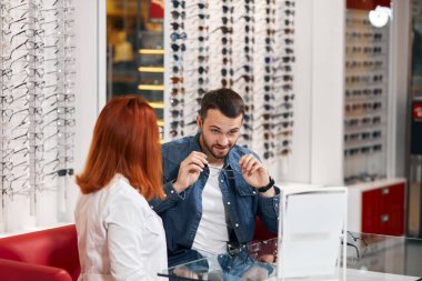Yakışıklı müşteri mağazadan uygun gözlük seçiyor.