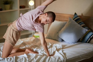 Genç bir kadının yatak odasında yoga egzersizleri yaptığı bir sabah..