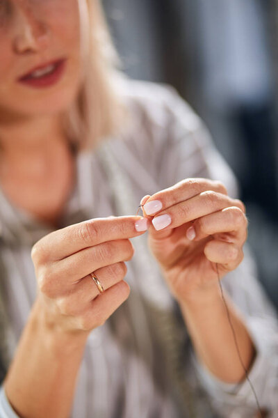 woman threading needle at home