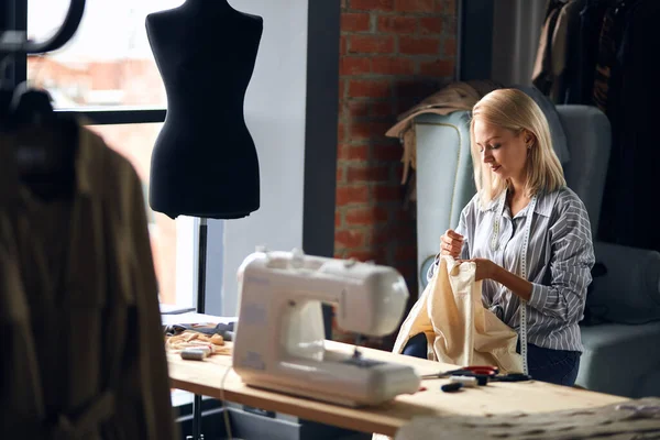 Jovem loira costureira reparação clientes roupas — Fotografia de Stock