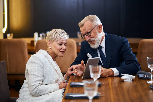 Portrait of cheerful senior couple on date, with laptop in hands chat and enjoy