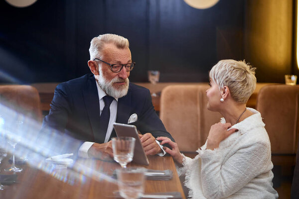 Portrait of cheerful senior couple on date, with laptop in hands chat and enjoy