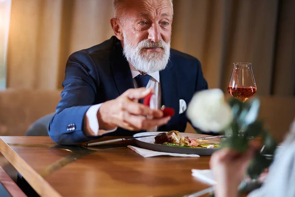 Mature elegant man proposing to a woman with rose — 图库照片