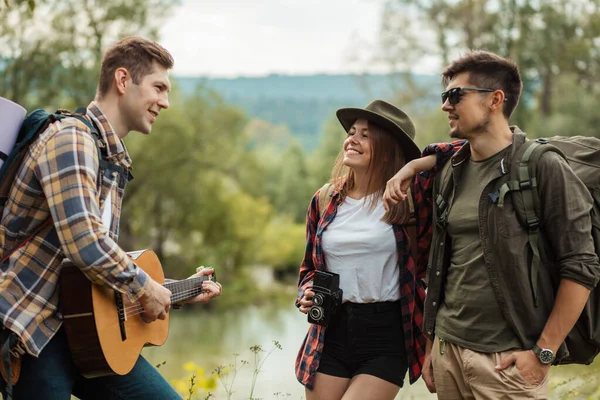 Jonge vrolijke paar genieten van het luisteren naar hun vrienden het spelen van de gitaar — Stockfoto