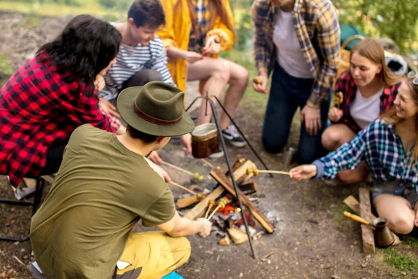 Jeunes touristes se réunissant autour de la bonfira et rôtissant des champignons — Photo