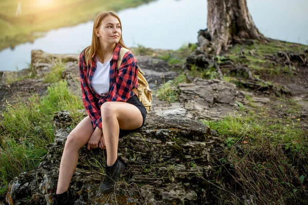Joven hermosa mujer rubia sentada en una roca con montañas — Foto de Stock