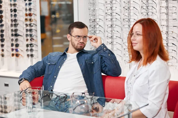 Ung skäggig man är inte nöjd med kvaliteten på glasögon — Stockfoto