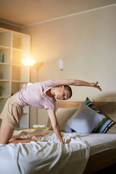 Молодая спортсменка занимается йогой на кровати, поднимает тело — стоковое фото