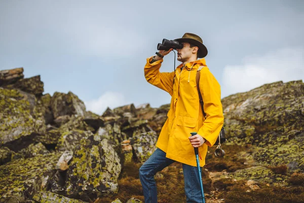 Ambizioso escursionista in abiti alla moda guardando attraverso il binocolo . — Foto Stock