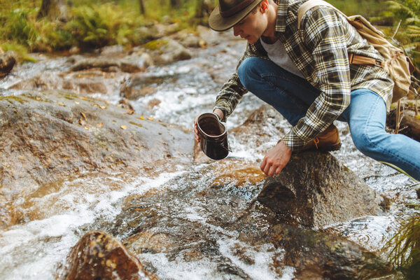 young man is taking water from river
