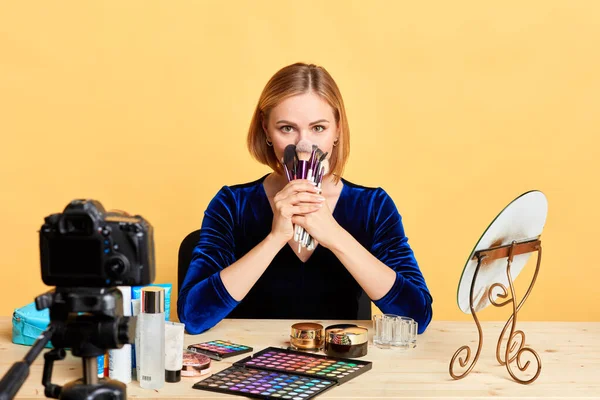 Attractive young famous female model holding bunch of new brushes near face — Stock Photo, Image