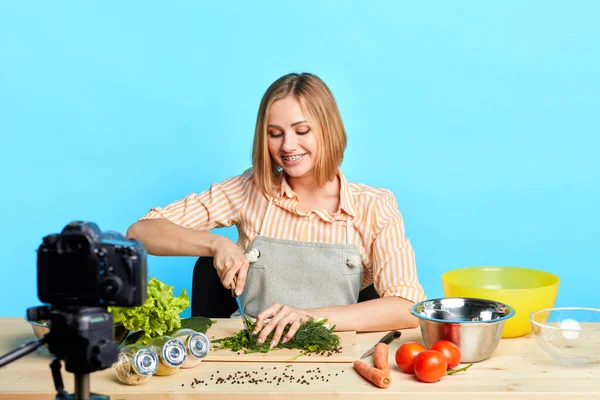 Jolie cuisinière démontre son talent culinaire, coupant des légumes crus frais — Photo