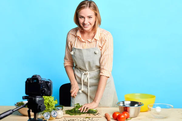 Lächelnde Hausfrau steht vor einem Holztisch voller frischem Gemüse — Stockfoto