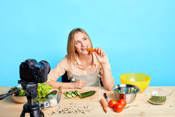 Donna dietista mordere carota fresca, guardando da parte con espressione sognante — Foto Stock