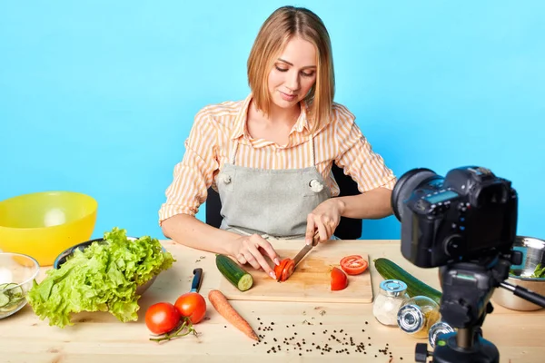 若い才能ある女性シェフは新鮮なトマトを切り取り、調理マスタークラスを記録します — ストック写真