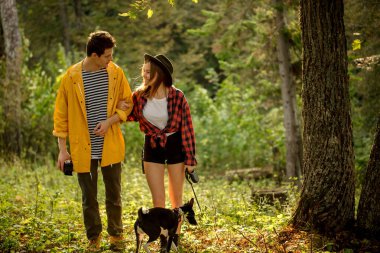 Young people with dog walking in autumn forest