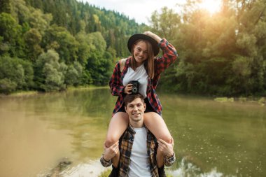 Neşeli sarışın güzel kadın erkek arkadaşının omuzlarında oturuyor..